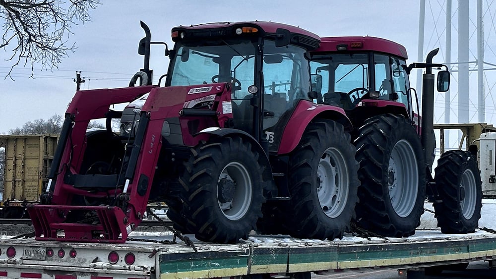 Two Kubota tractors being moved on a trailer